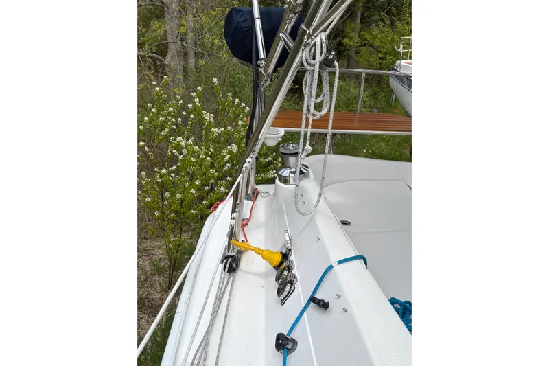Slide: The Image of 2009 Hunter 41 Deck Salon sailboat deck with rigging and winch in a wooded setting. - 29