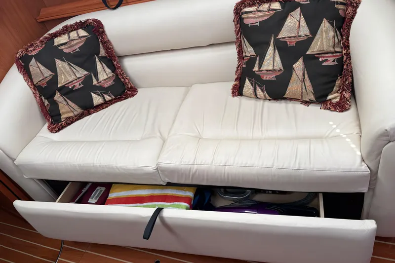 Slide: The Image of White sofa with sailboat-themed cushions and open storage drawer on a 2009 Hunter 41 Deck Salon. - 42