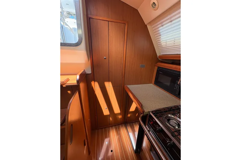 Slide: The Image of Interior of 2009 Hunter 41 Deck Salon, featuring wood cabinetry and kitchen appliances. - 57