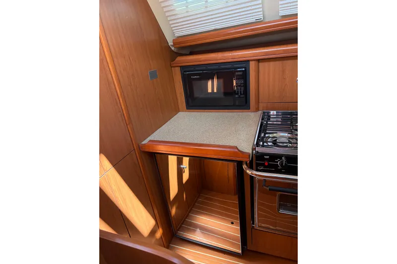 Slide: The Image of 2009 Hunter 41 Deck Salon kitchen with microwave, stove, and wooden cabinetry. - 59