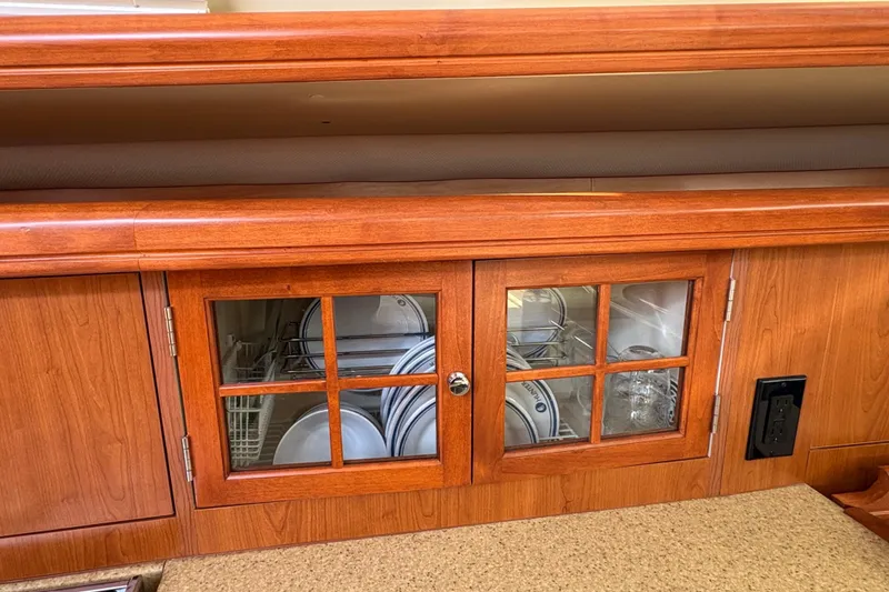 Slide: The Image of Wooden cabinet with glass doors, displaying neatly arranged dishes and glasses on a 2009 Hunter 41 Deck Salon. - 64
