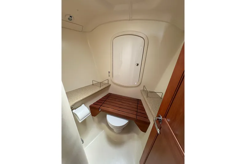 Slide: The Image of 2009 Hunter 41 Deck Salon bathroom with wooden seat and storage shelves. - 77
