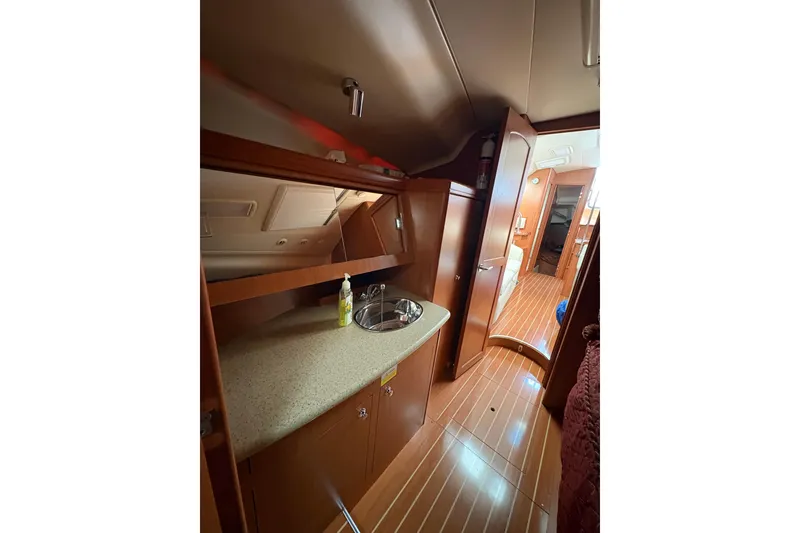 Slide: The Image of Interior of 2009 Hunter 41 Deck Salon yacht, featuring a compact kitchenette and wooden flooring. - 84