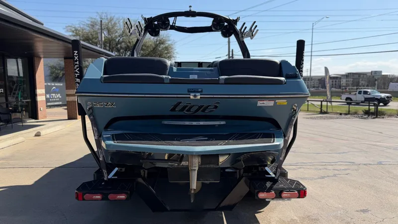 Slide: The Image of Rear view of a 2022 Tigé 25ZX boat in a parking lot. - 4