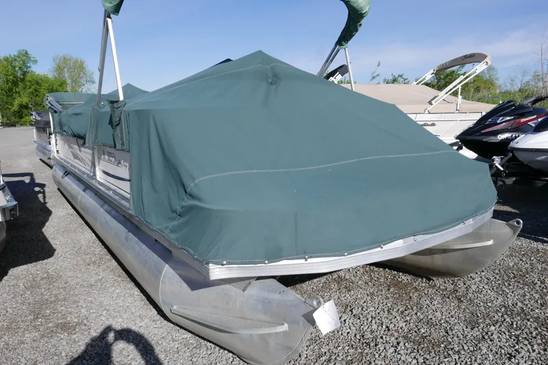 The Image of 2004 Sun Tracker Party Barge 240 pontoon boat with green cover, parked on gravel. - 0