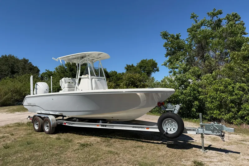 The Image of 2026 Pathfinder 2400 Open boat on trailer, parked outdoors with trees in background. - 0