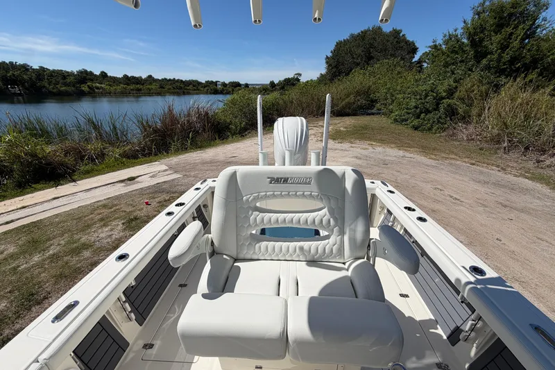 Slide: The Image of 2026 Pathfinder 2400 Open boat interior with white seating, near a scenic lakeside. - 13