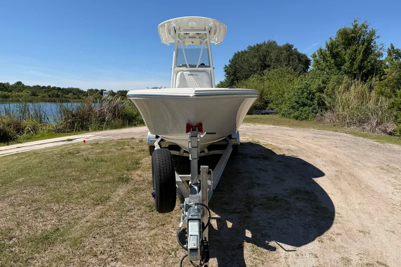 Slide: The Image of 2026 Pathfinder 2400 Open boat on trailer, parked near a scenic lake and greenery. - 2