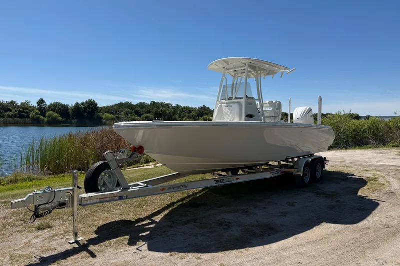 Slide: The Image of 2026 Pathfinder 2400 Open boat on trailer by a lake under clear blue sky. - 3