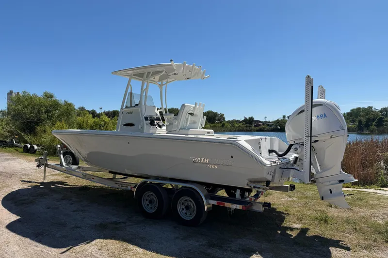 Slide: The Image of 2026 Pathfinder 2400 Open boat on trailer, parked near a lake under clear blue sky. - 4