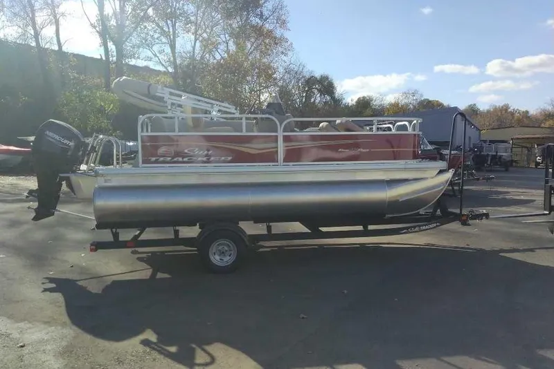 Slide: The Image of 2026 Sun Tracker Bass Buggy 16 XL Select pontoon boat on trailer, parked outdoors. - 78
