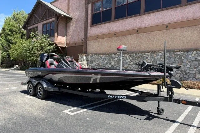 Slide: The Image of 2026 Nitro Z21 XL Pro boat on trailer in parking lot, near rustic building. - 2
