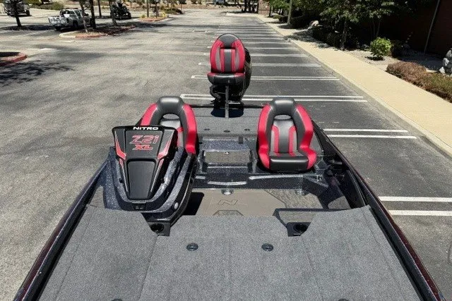 Slide: The Image of 2026 Nitro Z21 XL Pro boat with red and black seats in a parking lot. - 6