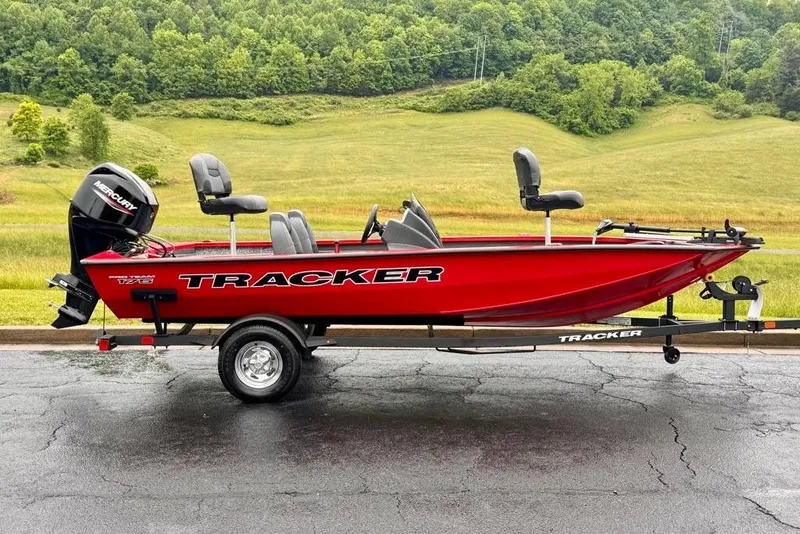 The Image of 2026 Tracker Pro Team 175 boat in vibrant red on a trailer, set against a lush green landscape. - 0