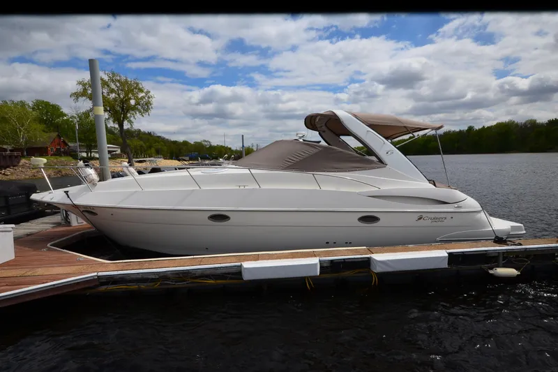 The Image of 2004 Cruisers Yachts 340 Express docked on a serene lake under a cloudy sky. - 0