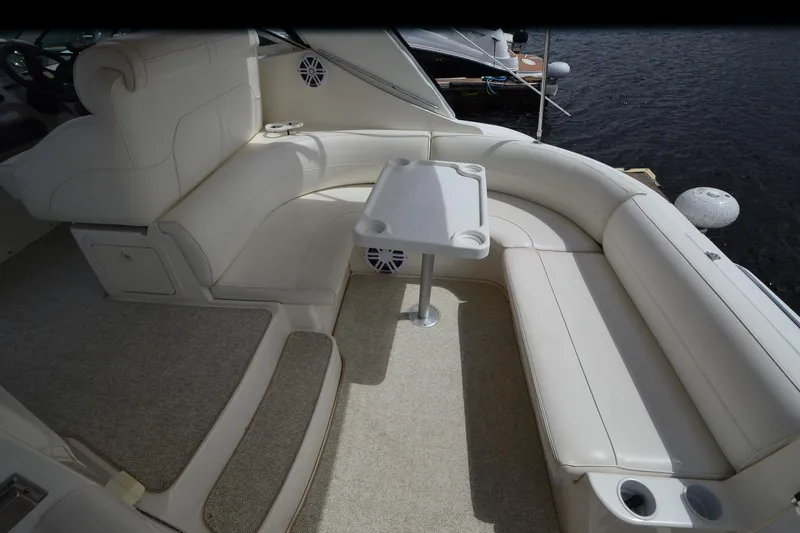 Slide: The Image of 2004 Cruisers Yachts 340 Express interior with white seating and table, docked by water. - 11