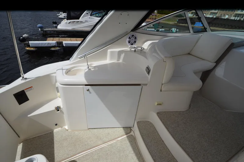 Slide: The Image of 2004 Cruisers Yachts 340 Express interior with seating and sink, docked by the water. - 17