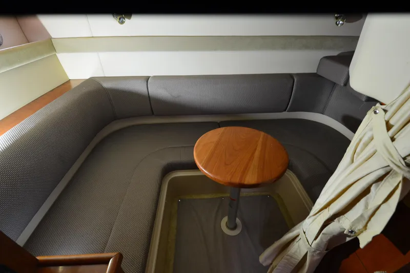 Slide: The Image of 2004 Cruisers Yachts 340 Express interior with gray seating and wooden table. - 22