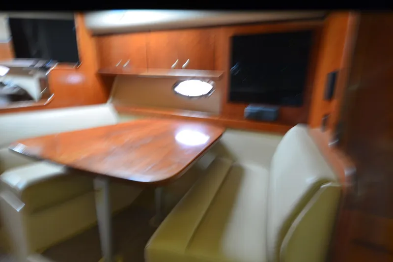 Slide: The Image of Interior of 2004 Cruisers Yachts 340 Express with wooden table and beige seating. - 24