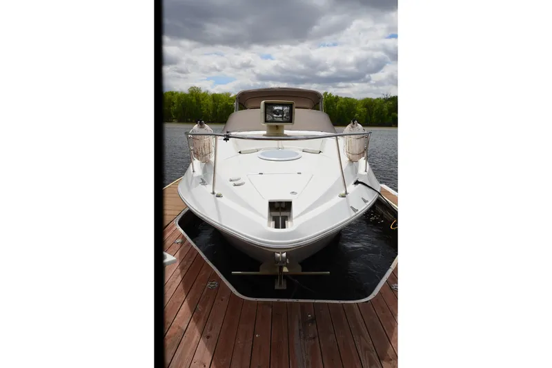 Slide: The Image of 2004 Cruisers Yachts 340 Express docked on a serene lake under cloudy skies. - 4