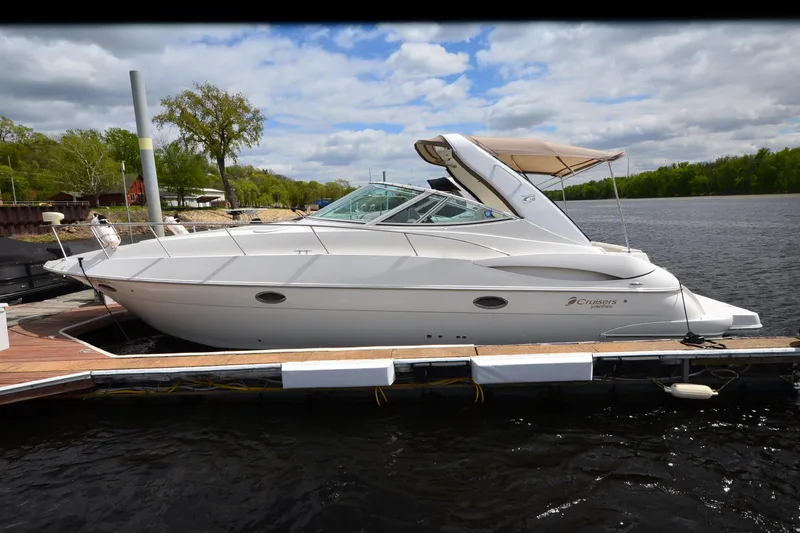 Slide: The Image of 2004 Cruisers Yachts 340 Express docked on a serene lake under a cloudy sky. - 6