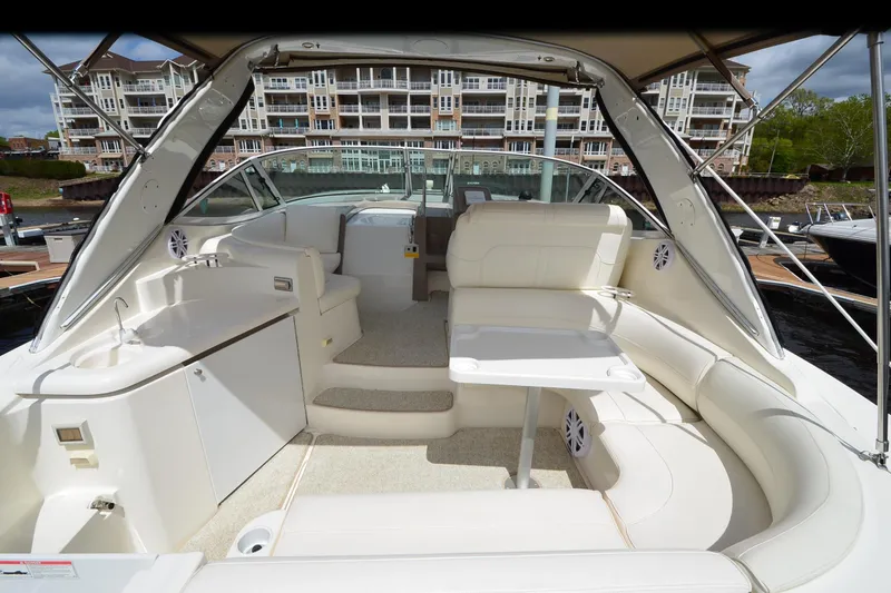 Slide: The Image of 2004 Cruisers Yachts 340 Express interior with white seating and table, docked at marina. - 9