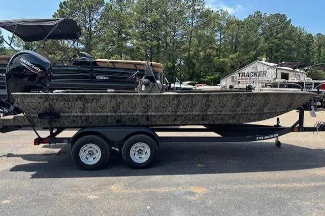 Slide: The Image of 2026 Tracker Grizzly 2072 CC boat on trailer, parked outdoors with trees in background. - 7