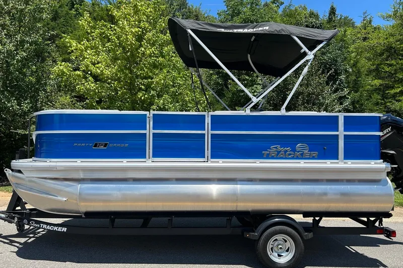 Slide: The Image of 2026 Sun Tracker Party Barge 18 DLX pontoon boat with canopy, parked on trailer. - 5