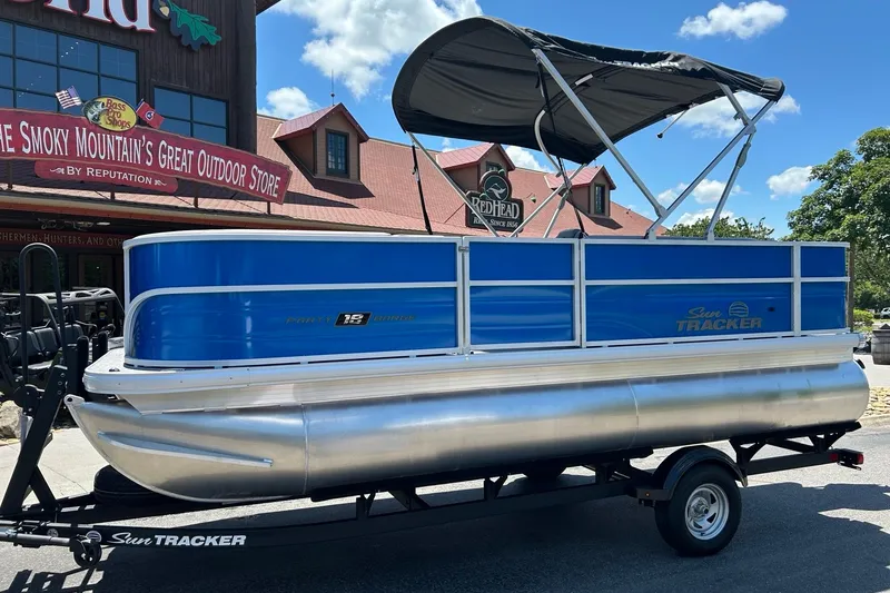 Slide: The Image of 2026 Sun Tracker Party Barge 18 DLX pontoon boat on trailer, outdoor store backdrop. - 1