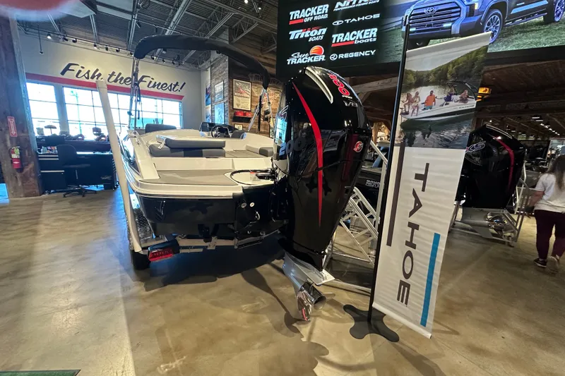 Slide: The Image of 2026 Tahoe T21 boat displayed indoors with promotional banners and signage. - 6