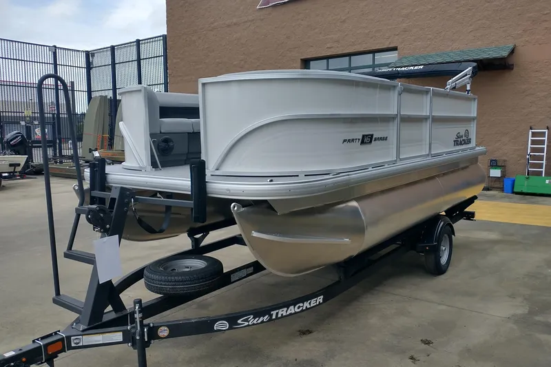 Slide: The Image of 2026 Sun Tracker Party Barge 16 DLX pontoon boat on trailer, parked outdoors. - 4