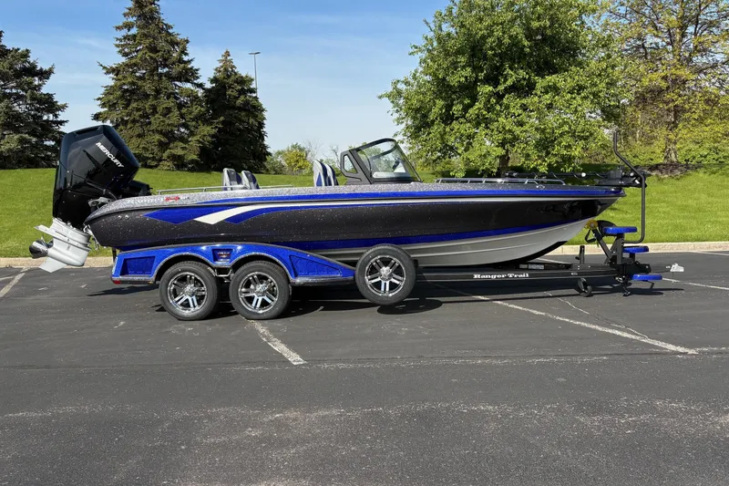 The Image of 2026 Ranger 621FS Cup-Equipped boat on trailer, parked outdoors with trees in background. - 0