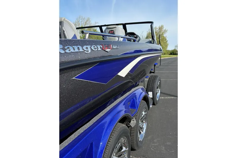 Slide: The Image of 2026 Ranger 621FS Cup-Equipped boat, blue and black design, parked outdoors. - 3