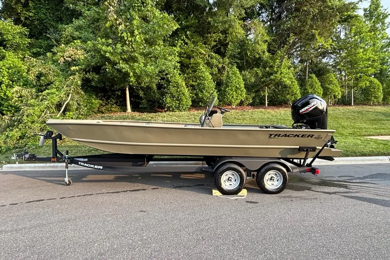 The Image of 2026 Tracker Grizzly 2072 CC boat on trailer, parked outdoors near lush greenery. - 0