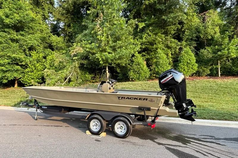 Slide: The Image of 2026 Tracker Grizzly 2072 CC boat on trailer, parked near lush greenery. - 4