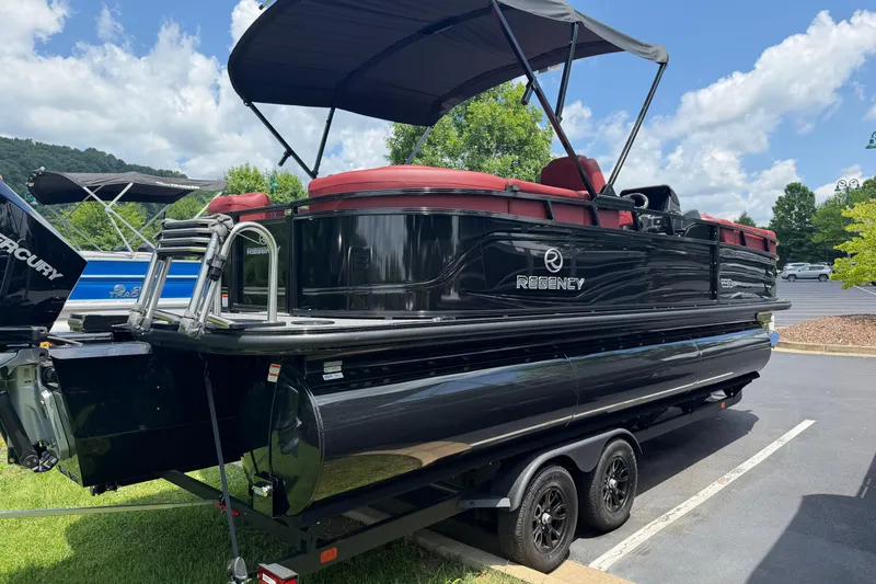 Slide: The Image of 2026 Regency 230 DL pontoon boat with black exterior and red seating on a trailer. - 3