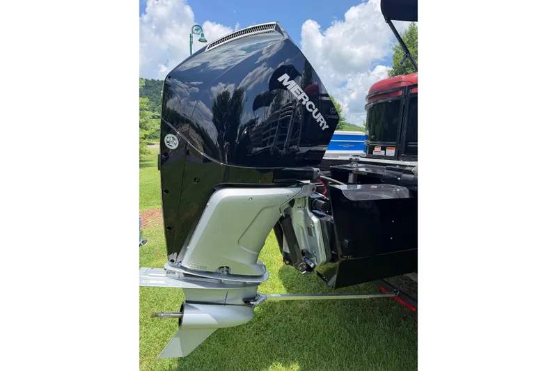 Slide: The Image of Outboard motor on a 2026 Regency 230 DL boat, parked on grass under a blue sky. - 17