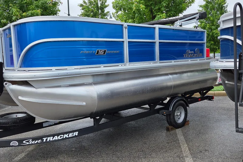 The Image of 2026 Sun Tracker Party Barge 16 DLX pontoon boat on trailer, parked outdoors. - 0