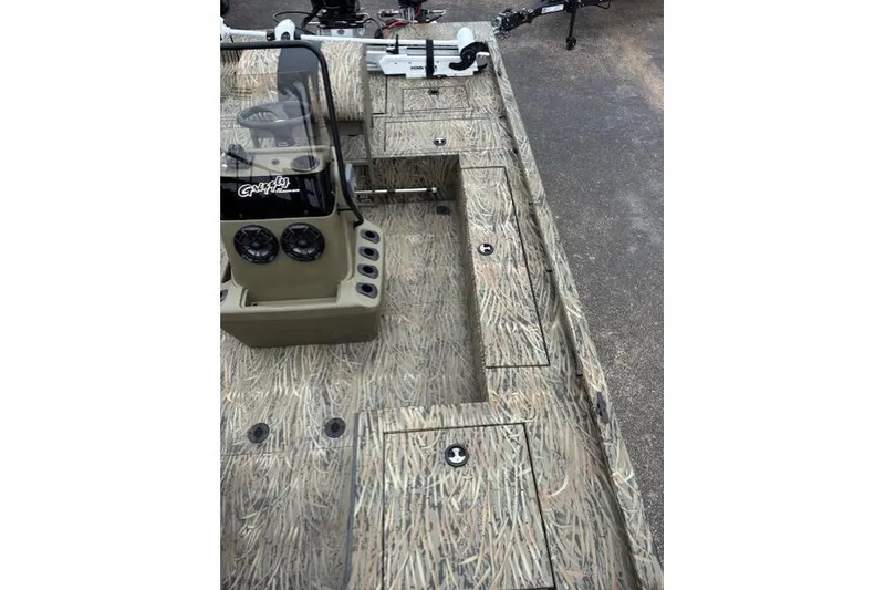Slide: The Image of 2026 Tracker Grizzly 2072 CC Sportsman Kicker boat interior with camouflage design and control panel. - 13