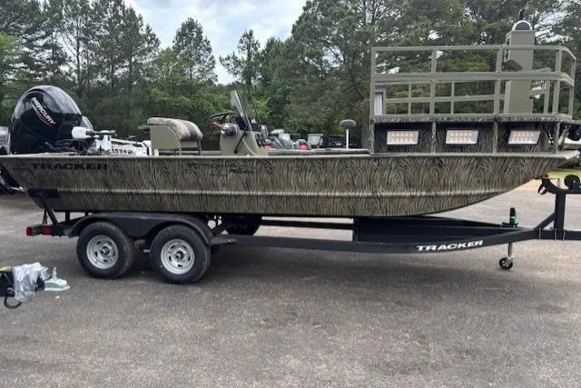 Slide: The Image of 2026 Tracker Grizzly 2072 CC Sportsman Kicker boat on trailer, camo design, parked outdoors. - 17
