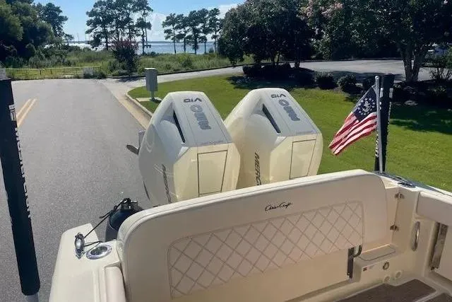 Slide: The Image of 2024 Chris-Craft Catalina 30 boat with twin engines and American flag, parked near a scenic waterfront. - 25