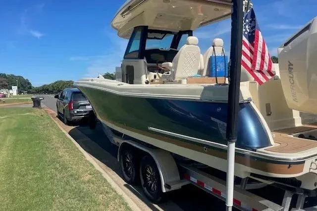 Slide: The Image of 2024 Chris-Craft Catalina 30 boat on trailer, parked roadside with American flag. - 29