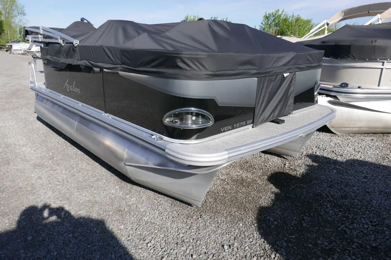 Slide: The Image of 2024 Avalon Venture Bow Fish 1575 pontoon boat with black cover on gravel. - 13