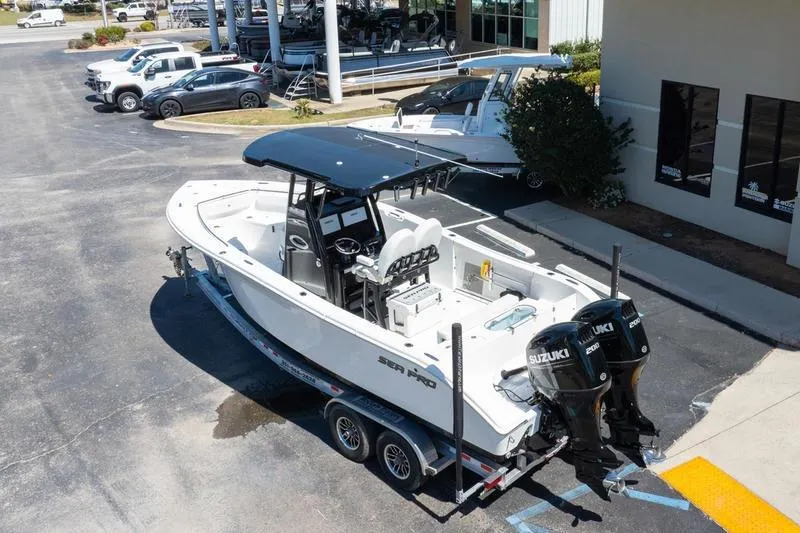 Slide: The Image of 2025 Sea Pro 262 Offshore boat with dual Suzuki engines on a trailer in a parking lot. - 11