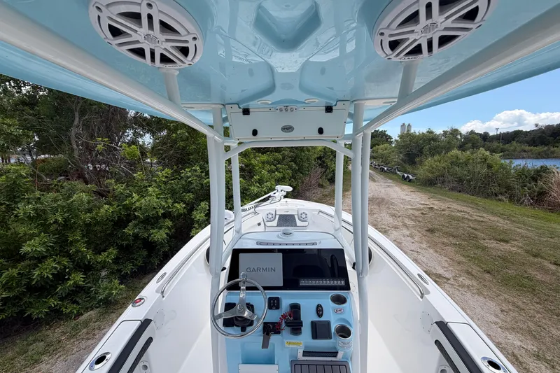 Slide: The Image of 2024 Tidewater 210 CC Adventure boat interior with Garmin navigation, speakers, and lush greenery backdrop. - 14