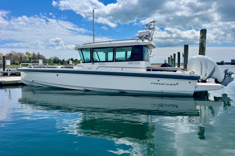 The Image of 2019 Axopar 28 Cabin boat docked on calm water under a partly cloudy sky. - 0