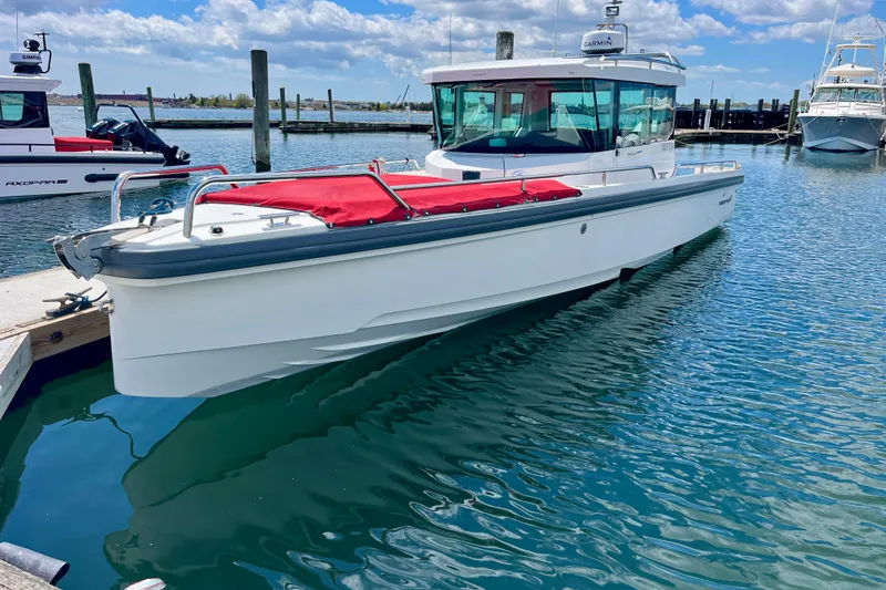 Slide: The Image of 2019 Axopar 28 Cabin boat docked in a marina under a blue sky. - 1