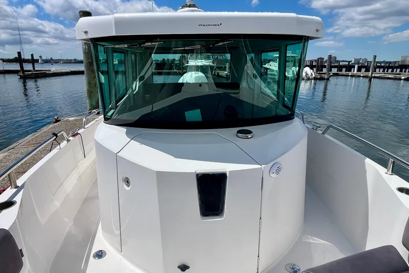 Slide: The Image of 2019 Axopar 28 Cabin boat docked at marina under blue sky. - 10