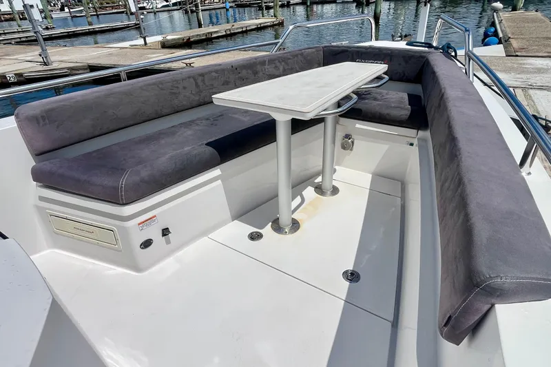 Slide: The Image of 2019 Axopar 28 Cabin boat with cushioned seating and table, docked at marina. - 12