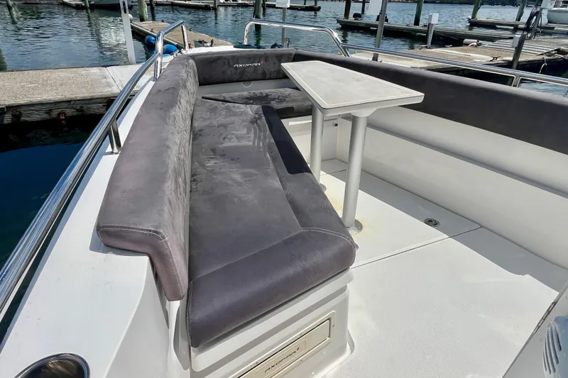 Slide: The Image of 2019 Axopar 28 Cabin boat with cushioned seating and table, docked at marina. - 13